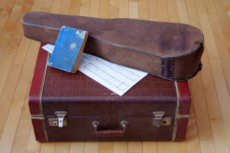 antique blue book with old violin case and sheet music on vintage brown leather suitcaseの写真素材