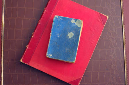 antique red and blue books on vintage brown leather suitcase with copy spaceの写真素材