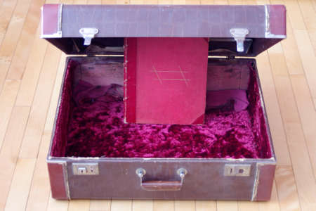open large vintage brown suitcase with red velvet and bookの写真素材