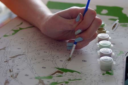 teenager painting pain by number with cell phoneの写真素材