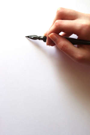 hand holding a black fountain pen on white paper with copy spaceの写真素材