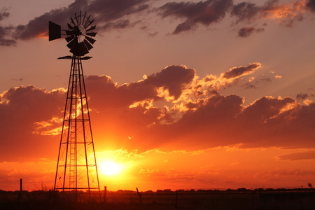 Beautiful silhouette of a windmill during a pretty sunsetの写真素材