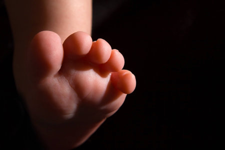 Newborn foot on a dark background