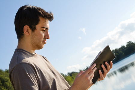 Man reading Bible by lakeの写真素材