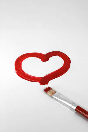 A red painted heart with paintbrush on whiteの写真素材