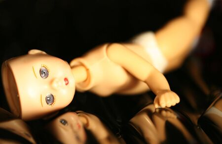 A doll with missing parts posed on a reflecting black backgroundの写真素材