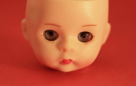 A close up of a doll's head on a red backgroundの写真素材