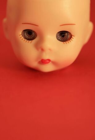 A close up of a doll's head with a red backgroundの写真素材