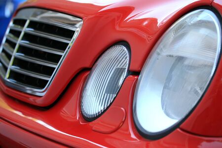 A close up of a red sports car grill and headlights