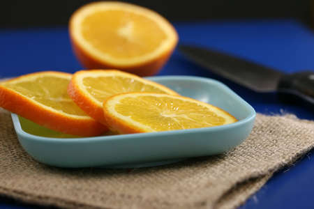 Orange slices on a plate on a blue table の写真素材