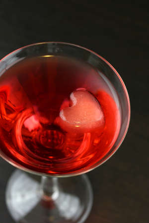 A red martini cocktail with a heart shaped ice cubesの写真素材