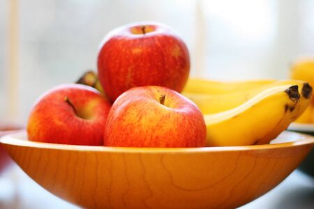 High key image of a bowl full of apples and bananasの写真素材