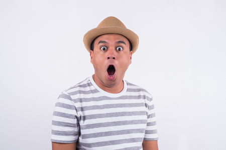 Young asian man with hat feels shock and surprise with overly face expression and looking on blank space.の写真素材