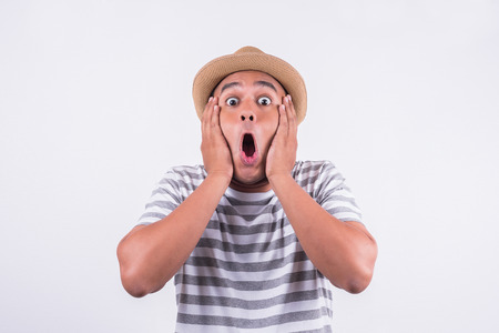 Young Asian man with hat feels shock and surprise with overly face expression.の写真素材