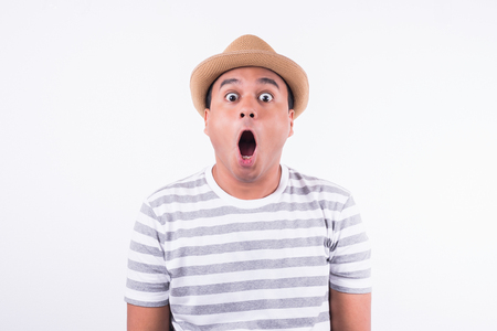 Young Asian man with hat feels shock and surprise with overly face expression.の写真素材