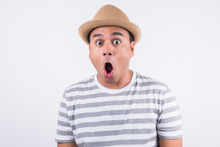Young Asian man with hat feels shock and surprise with overly face expression.の写真素材