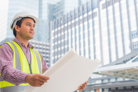 Young asian civil engineer working on building construction.Construction Worker looking paper work of building.の写真素材