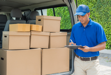 Young asian delivery in blue uniforms holding a clipboard.の写真素材
