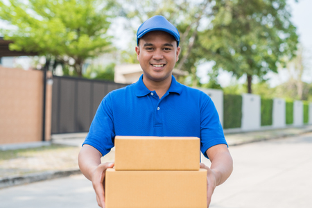 Blue Delivery man holding parcel cardboard box.の写真素材
