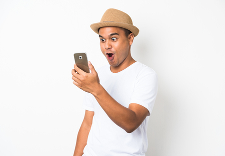 Young asian man with hat looking at smartphone and feels shockedの写真素材
