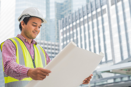 Young asian civil engineer working on building construction.Construction Worker looking paper work of building.の写真素材