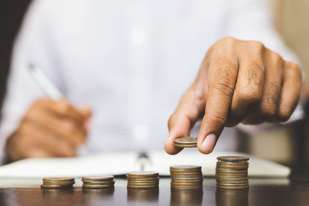 Saving money concept preset by Male hand putting money coin stack growing business.