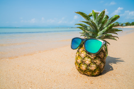 Pineapple with sunglasses on tropical beach background.の写真素材