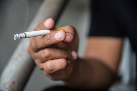 Close up male hand holding a cigarette.の写真素材