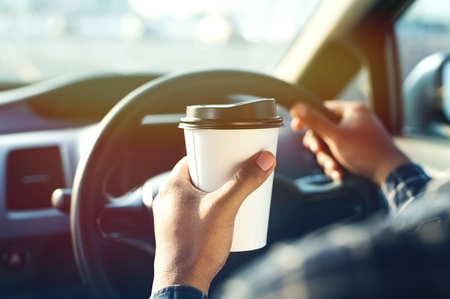 Man holding coffee paper cup in carの写真素材