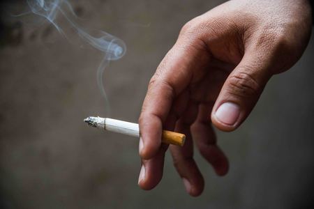 Close up male hand holding a cigarette.の写真素材