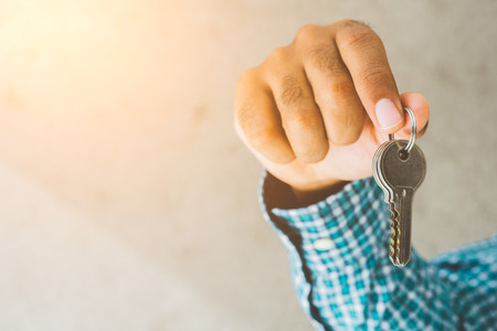 Close up hand holding key in house.
