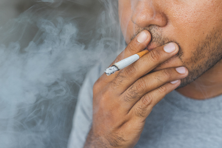 Close up young man smoking a cigarette.の写真素材