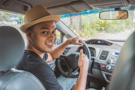 Young asian man showing thumbs up while driving car with copy space.の写真素材