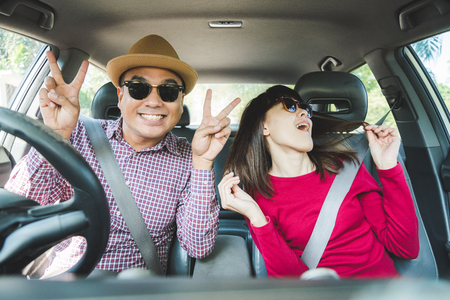 Front view of Funny moment couple asian man and woman sitting in car. Enjoying travel concept.の写真素材