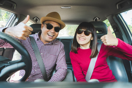 Front view of Funny moment couple asian man and woman sitting in car. Enjoying travel concept.の写真素材