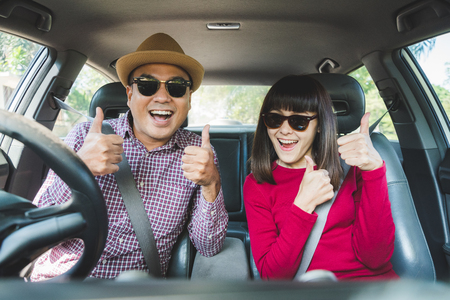 Front view of Funny moment couple asian man and woman sitting in car. Enjoying travel concept.の写真素材