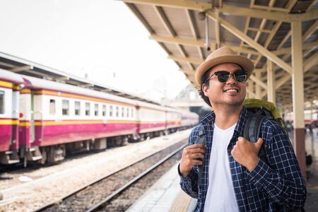 Traveler man standing and waits train on railway platform