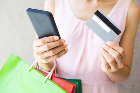 Close up of woman hand holding shopping bags, smartphone and credit card.の写真素材