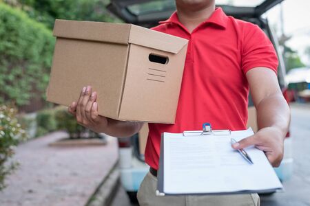 Delivery man in red uniform holding clipboardの写真素材
