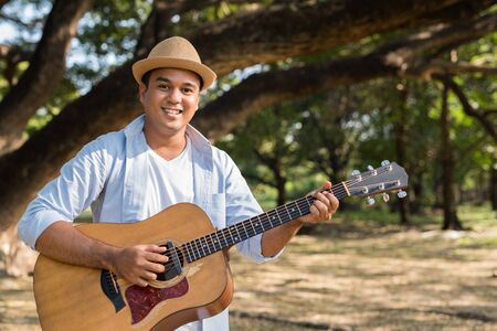 Young asian man playing guitar the park