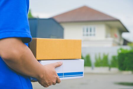 Close up Delivery man in blue uniforms holding parcel cardboard box.