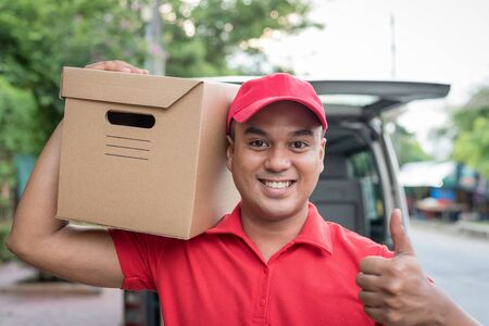 Delivery concept - postman in red uniform holding packageの写真素材