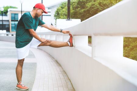 Young asian man stretching legs before run with copy space.の写真素材