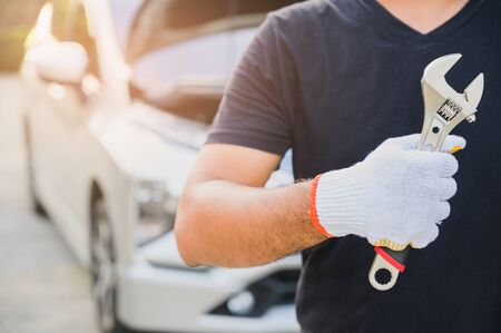 Car machanic holding wrench near car. Car maintenance concept.の写真素材