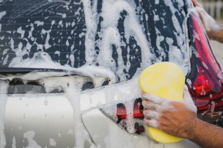 Man cleaning washing car with sponge and foamの写真素材