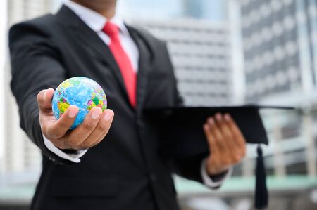 Close up Businessman holding Global Earth and Graduation cap in hand for education concept.の写真素材