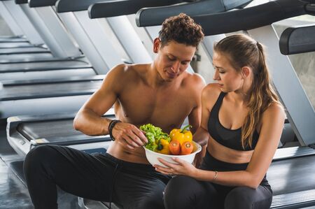 Couple fitness man and women workout and holding bowl of vegetable for healthy food concept.の写真素材