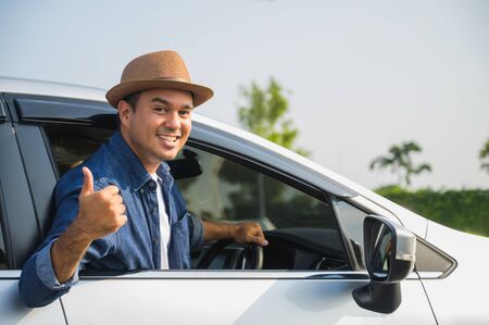 A traveler wearing a hat is driving a car and then pulling himself out of the car window. And thumbs...