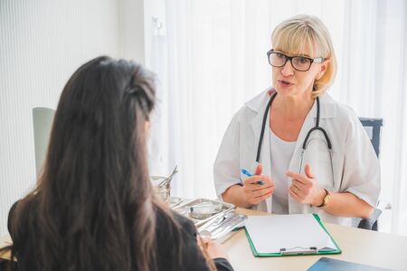 Senior female doctor meet the patient discussing and making notes about symptom problem. Health care and client service in medicine concept.の写真素材