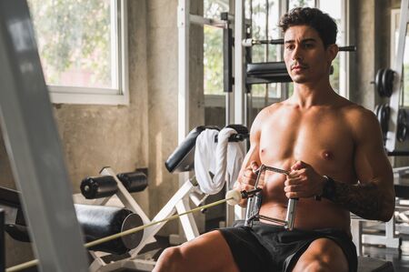 Strong muscular man workout in gym doing exercises at biceps.  Weight training concept.